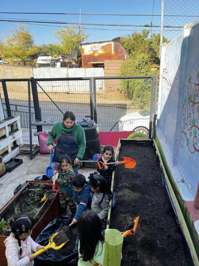 Kinderen scheppen aarde voor de planten bij Mundo Feliz